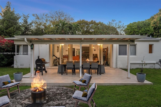 rear view of property featuring a fire pit, crawl space, a lawn, outdoor dining space, and a patio area