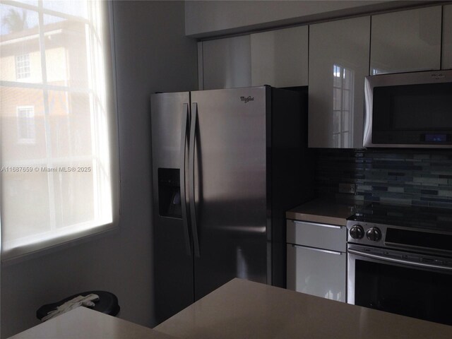 kitchen with appliances with stainless steel finishes, decorative backsplash, and rail lighting