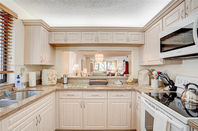 kitchen featuring sink, white appliances, a textured ceiling, and a notable chandelier