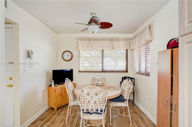 dining space with a textured ceiling, light wood-type flooring, and ceiling fan