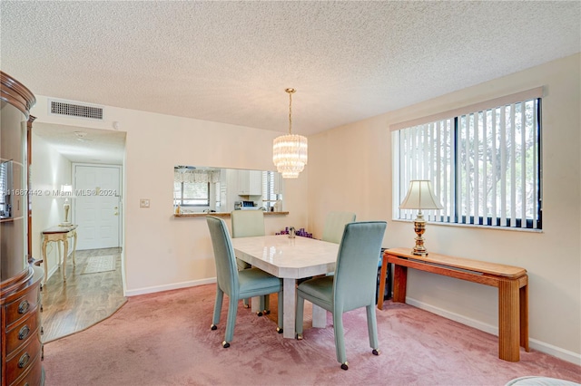 carpeted dining area with an inviting chandelier and a textured ceiling