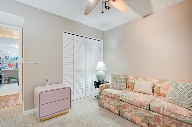 living room with ceiling fan, a textured ceiling, and carpet floors