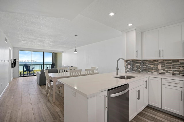 kitchen with sink, a water view, white cabinets, dishwasher, and kitchen peninsula