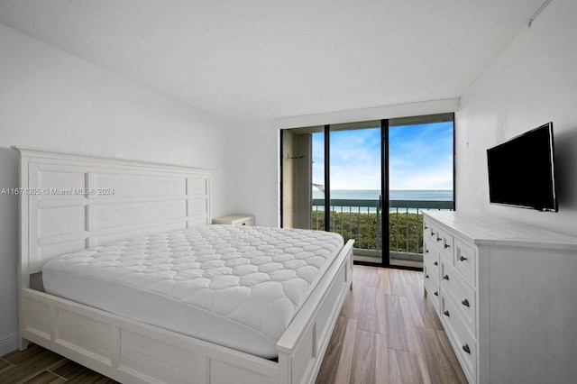 bedroom featuring light wood-type flooring, access to outside, and floor to ceiling windows