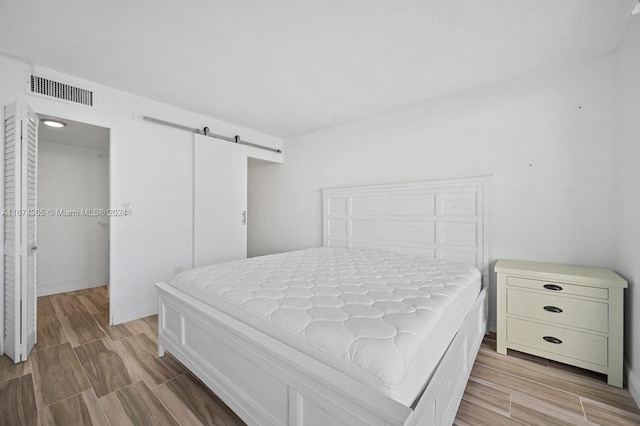 bedroom with a closet, a barn door, and wood-type flooring