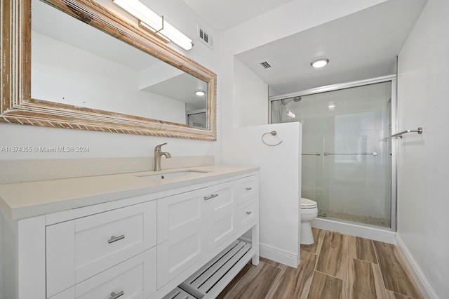 bathroom with toilet, vanity, and a shower with door