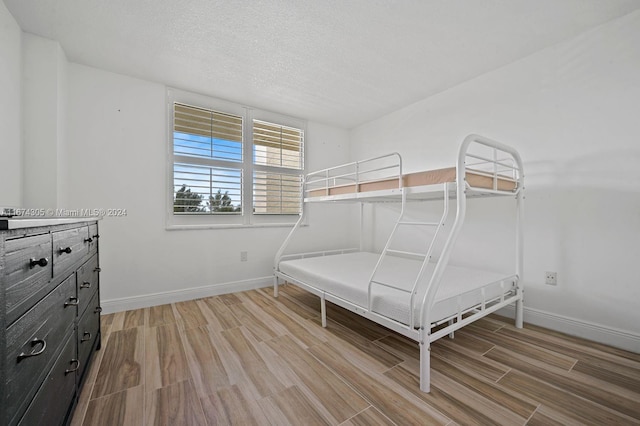 unfurnished bedroom with light wood-type flooring and a textured ceiling