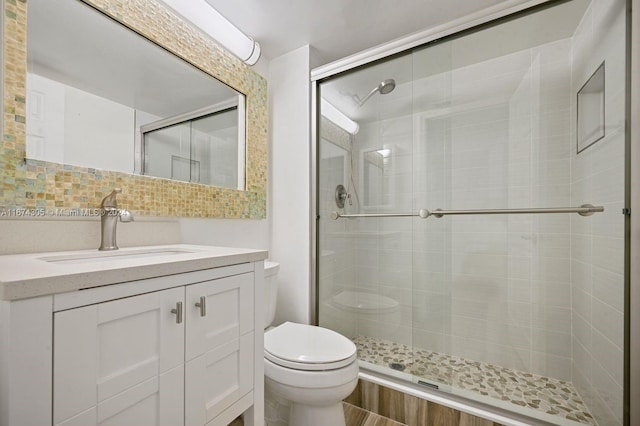 bathroom with decorative backsplash, vanity, toilet, and a shower with door