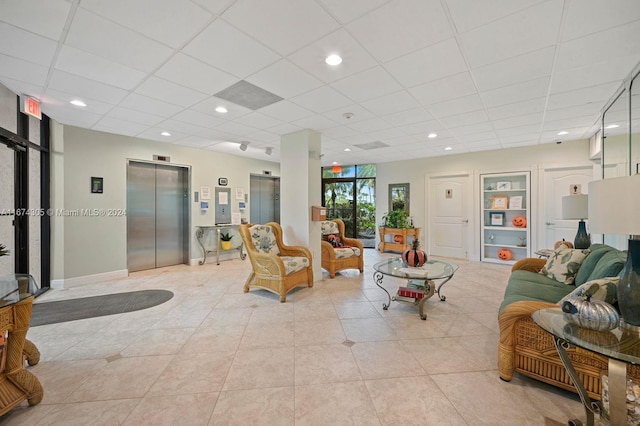 living room with a paneled ceiling, elevator, and light tile patterned floors