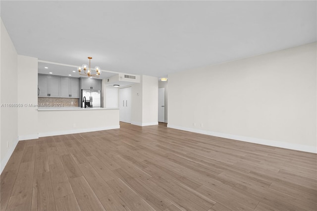 unfurnished living room featuring light hardwood / wood-style flooring and a chandelier