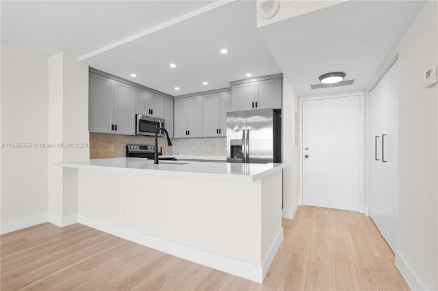 kitchen with light hardwood / wood-style flooring, kitchen peninsula, and stainless steel appliances