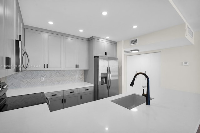 kitchen with gray cabinets, sink, appliances with stainless steel finishes, and decorative backsplash