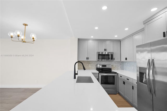 kitchen with decorative light fixtures, stainless steel appliances, sink, and gray cabinetry