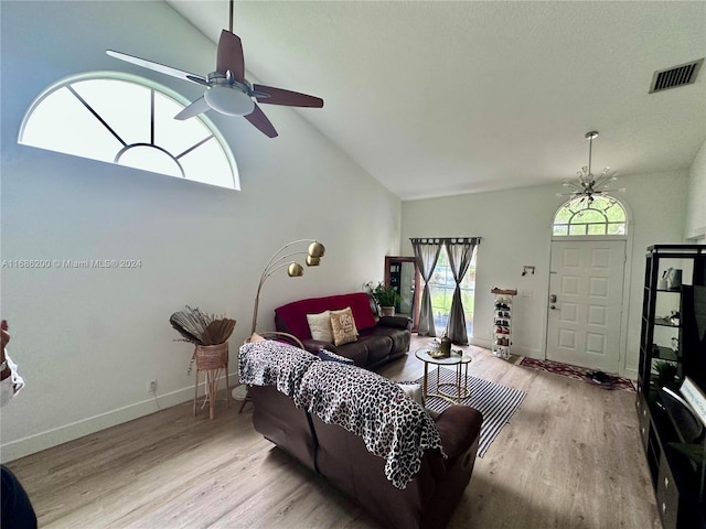 living room with light hardwood / wood-style floors, high vaulted ceiling, and ceiling fan with notable chandelier