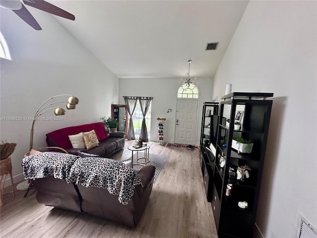 living room with lofted ceiling, wood-type flooring, and ceiling fan with notable chandelier