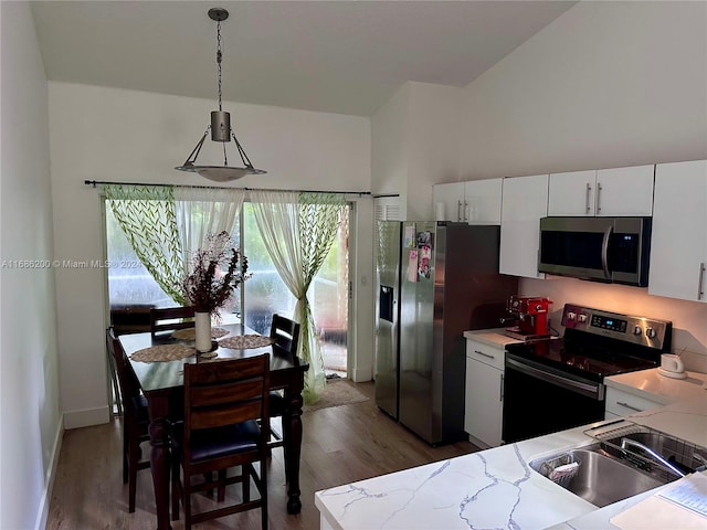 kitchen featuring dark wood-type flooring, stainless steel appliances, sink, pendant lighting, and white cabinetry