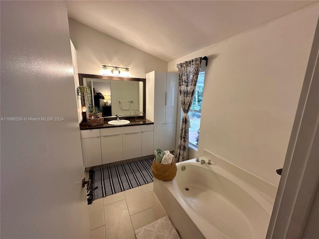 bathroom featuring vanity, vaulted ceiling, tile patterned flooring, and a bathing tub