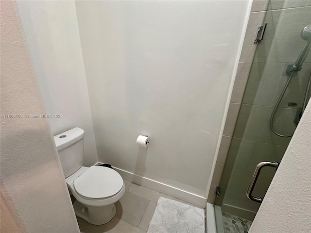 bathroom with tile patterned flooring, toilet, and an enclosed shower