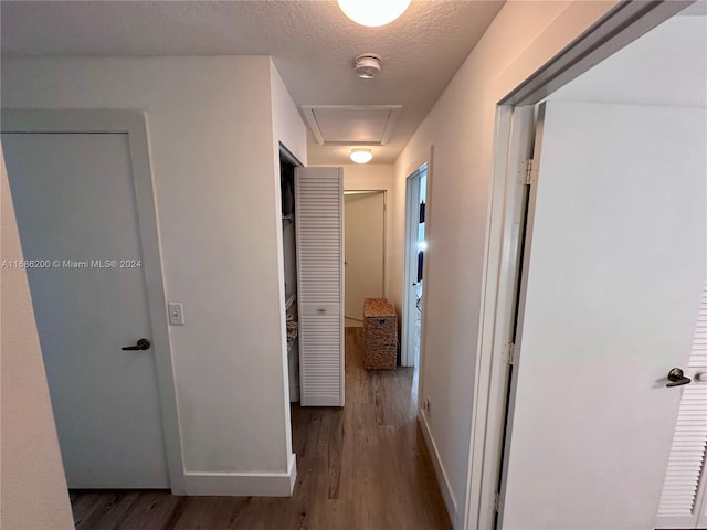 corridor with a textured ceiling and dark wood-type flooring