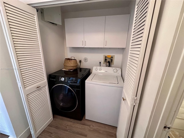 washroom with hardwood / wood-style floors, washer and clothes dryer, and cabinets