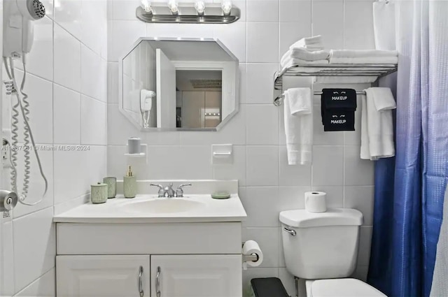 bathroom with toilet, tasteful backsplash, vanity, and tile walls