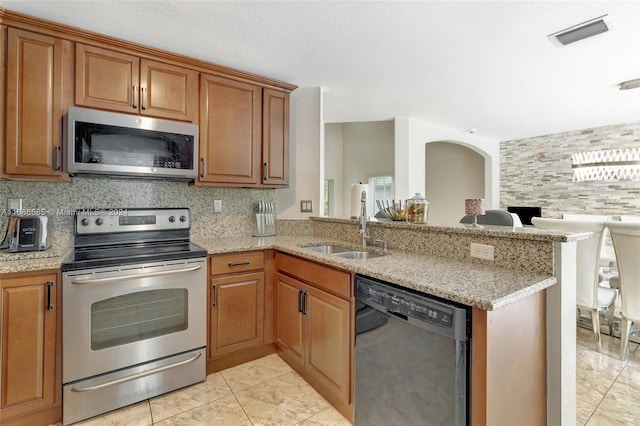 kitchen featuring backsplash, kitchen peninsula, sink, and stainless steel appliances