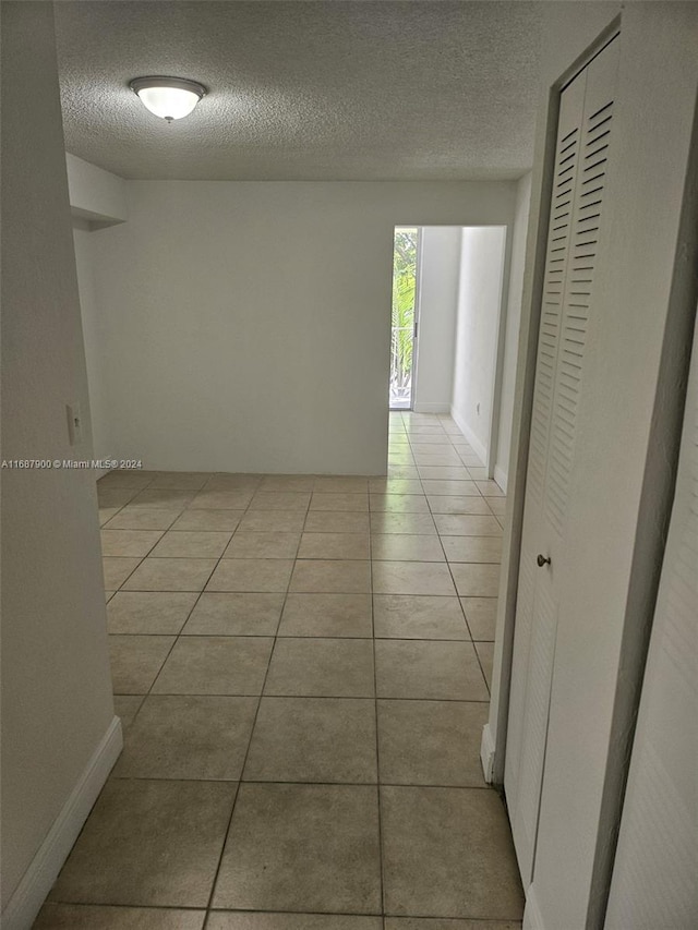 hallway featuring a textured ceiling and light tile patterned floors