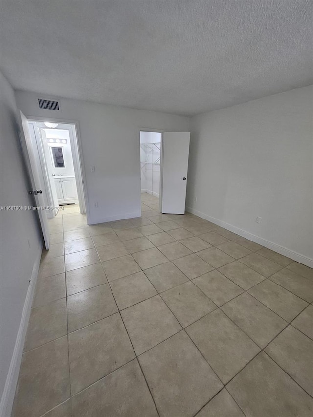 unfurnished room with a textured ceiling and light tile patterned floors