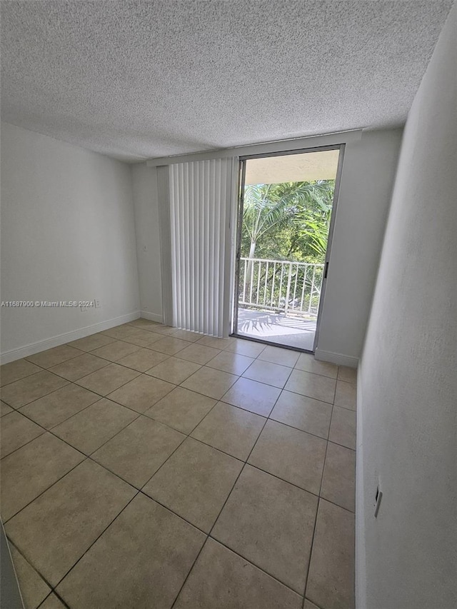 empty room featuring light tile patterned flooring and a textured ceiling