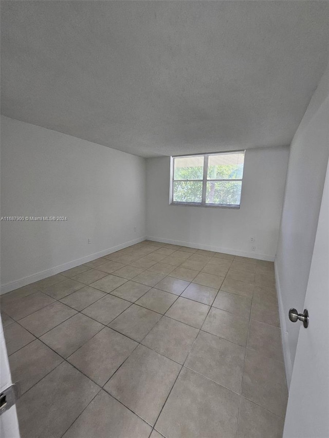 empty room featuring a textured ceiling and light tile patterned floors