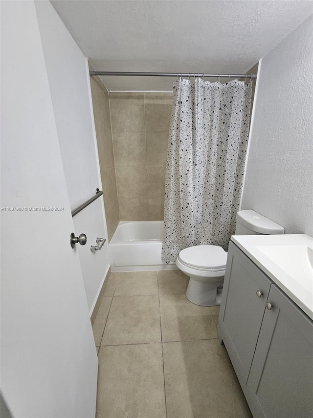 full bathroom with a textured ceiling, shower / bath combo, toilet, tile patterned floors, and vanity