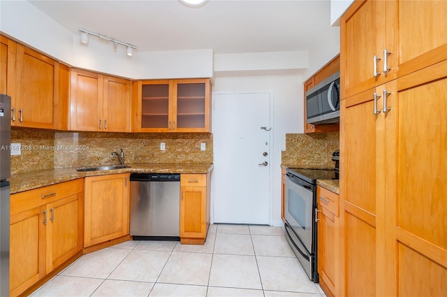 kitchen featuring tasteful backsplash, stainless steel appliances, stone counters, and sink