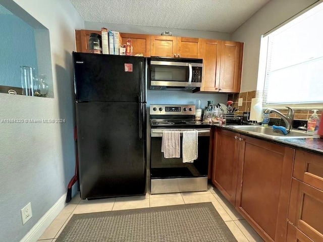 kitchen with sink, light tile patterned floors, a textured ceiling, tasteful backsplash, and stainless steel appliances