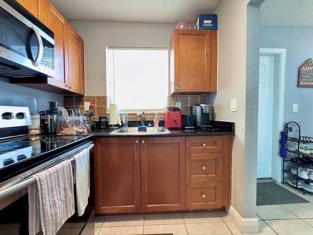 kitchen with tasteful backsplash, a textured ceiling, stainless steel appliances, sink, and light tile patterned floors