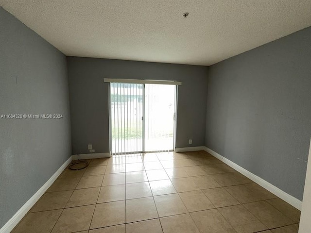 tiled empty room featuring a textured ceiling