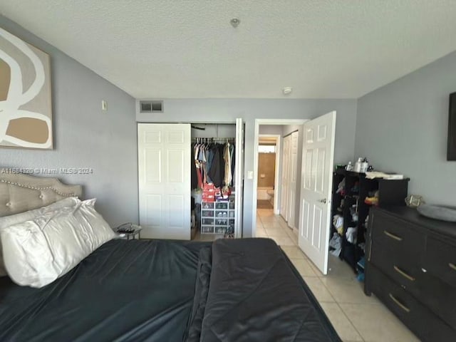 tiled bedroom with a textured ceiling and a closet