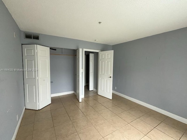 unfurnished bedroom with light tile patterned floors and a textured ceiling