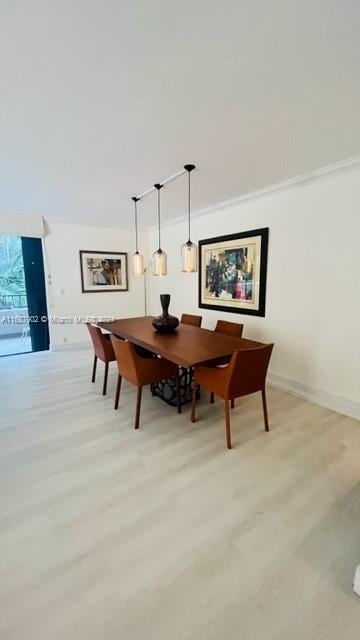 dining space featuring ornamental molding and light wood-type flooring