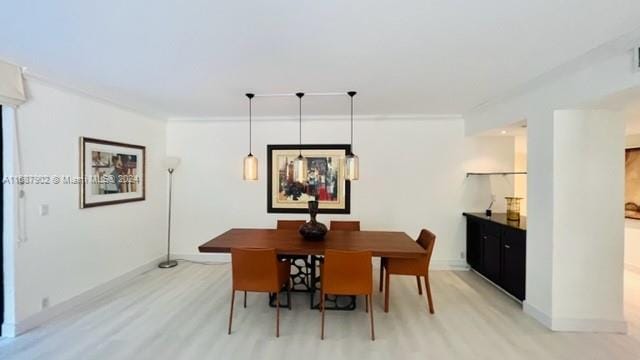 dining area with light hardwood / wood-style floors and ornamental molding