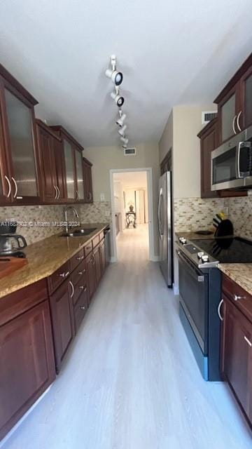 kitchen with stainless steel appliances, backsplash, sink, dark brown cabinetry, and light wood-type flooring