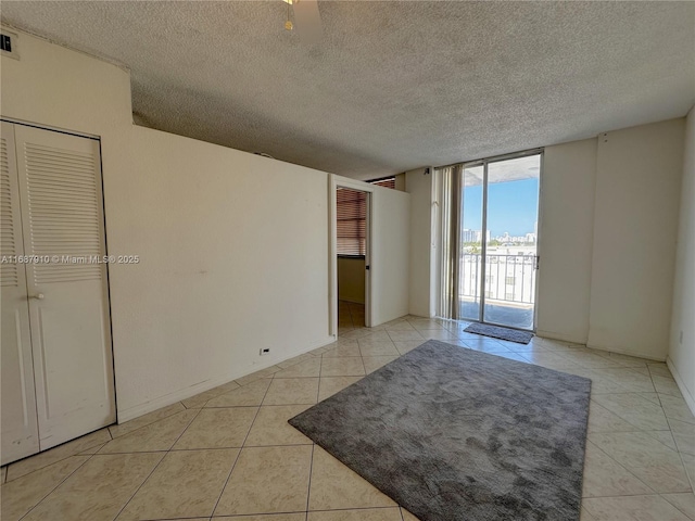 tiled empty room featuring floor to ceiling windows and a textured ceiling