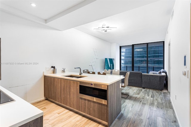 kitchen with light hardwood / wood-style flooring, sink, floor to ceiling windows, and kitchen peninsula