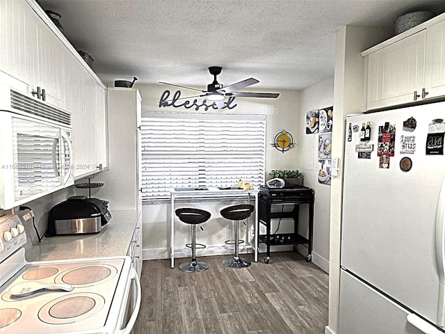 kitchen with white cabinets, ceiling fan, a textured ceiling, dark wood-type flooring, and white appliances