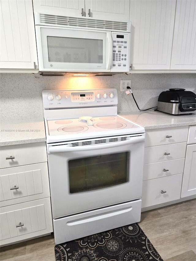 kitchen with light hardwood / wood-style flooring, tasteful backsplash, white appliances, and white cabinets