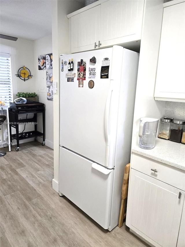 kitchen featuring light hardwood / wood-style flooring, white refrigerator, and white cabinets