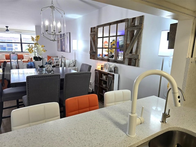 dining space with sink and ceiling fan with notable chandelier