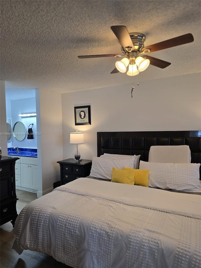 bedroom with ceiling fan, a textured ceiling, and ensuite bath