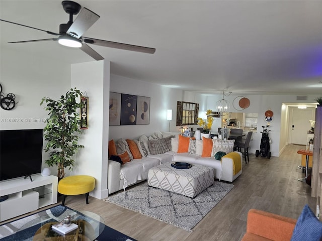 living room with hardwood / wood-style flooring and ceiling fan with notable chandelier