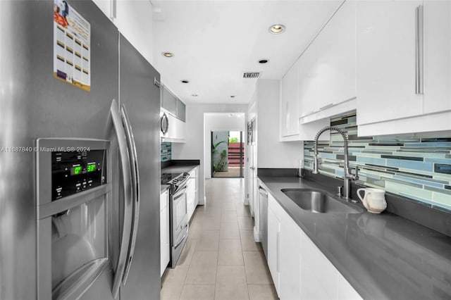 kitchen with light tile patterned floors, appliances with stainless steel finishes, sink, and white cabinets