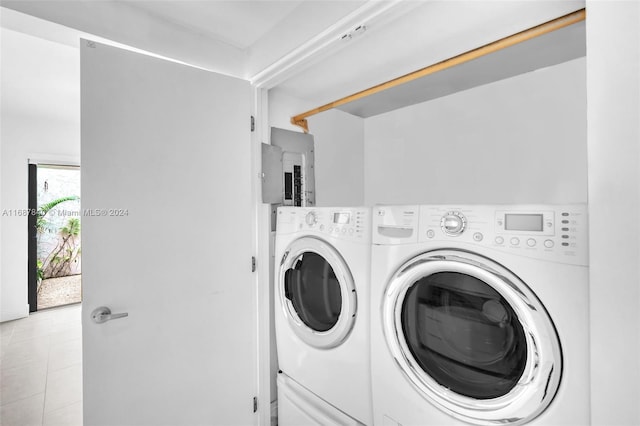 washroom featuring electric panel, light tile patterned flooring, and washing machine and dryer